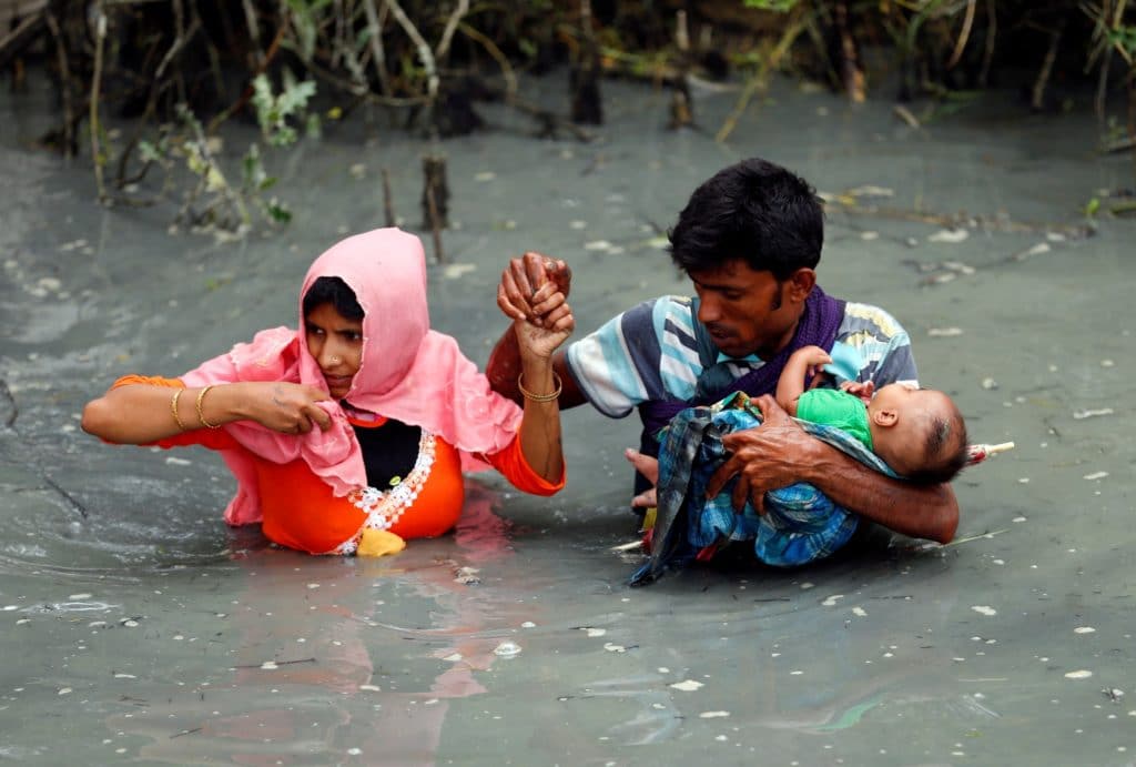 Una coppia di rifugiati rohingya attraversa il fiume Naf, in Bagladesh per fuggire dalle persecuzioni dei militari birmani.