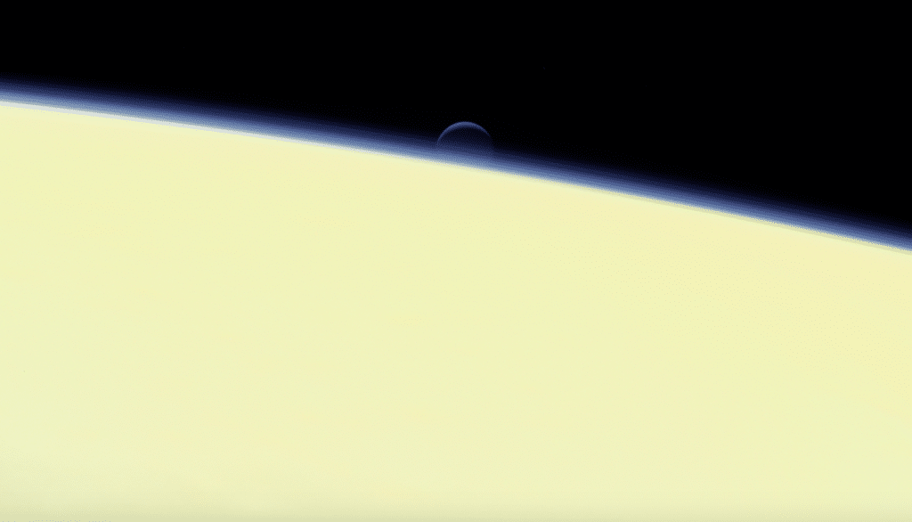 Una delle ultime immagini inviate a Terra dalla sonda Cassini mostra la luna di Saturno Encelado sullo sfondo dell'atmosfera del pianeta gassoso