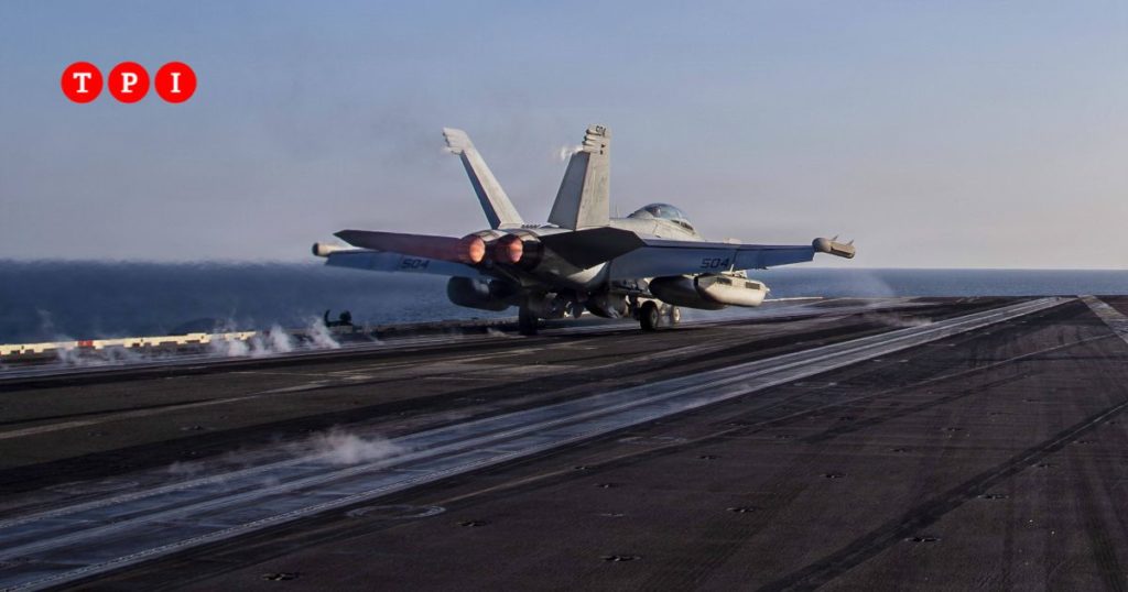 Base militare colpita di notte con esplosioni in cielo, fuoco e fumo su strutture in ambiente desertico